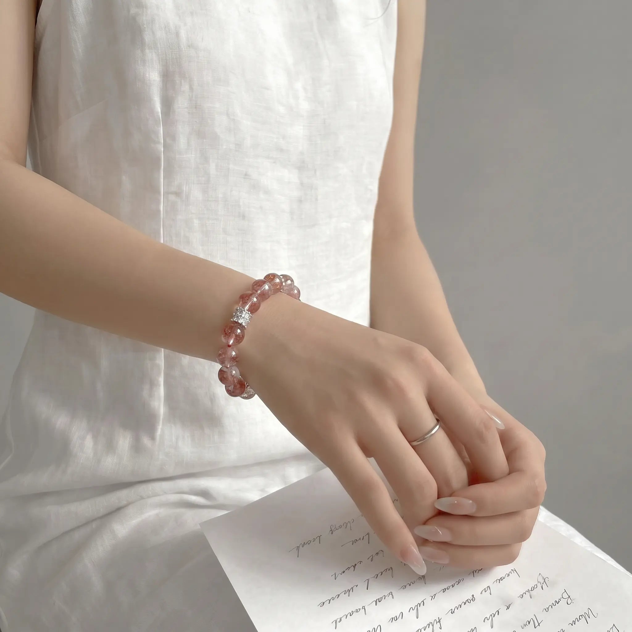 Right-side view of an elegant seated lady resting hands over her thighs to showcase the premium quartz crystal bracelet.
