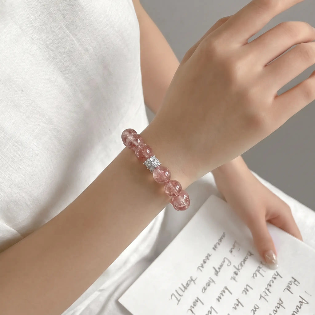 Right-side profile close-up shot focusing on a female wrist decorated with a pink strawberry quartz bracelet.