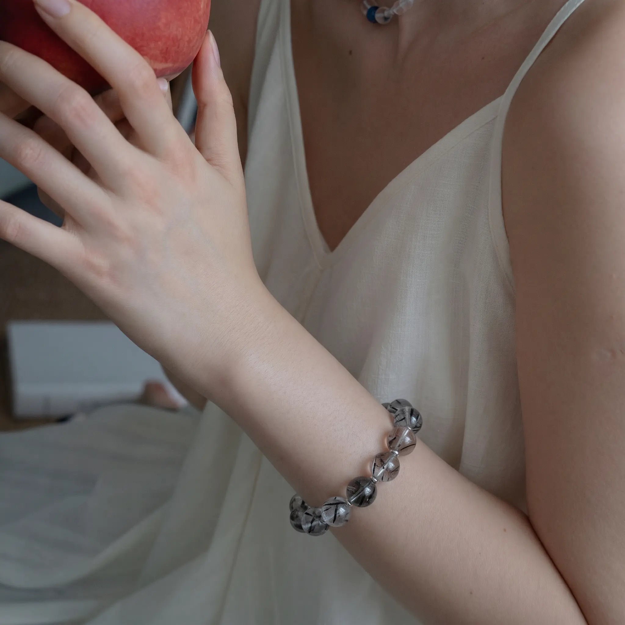 Left-side profile close-up shot focusing on a female wrist adorned with a black rutilated quartz bracelet.