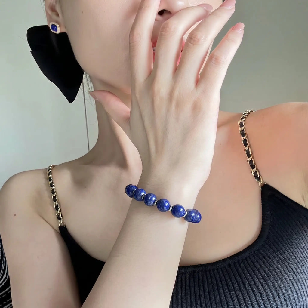 Close-up portrait view of a woman wearing the Celestial Lapis Bracelet with her left hand gracefully covering her lips.