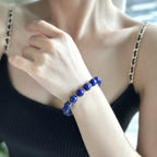 Front close-up view from collarbone to chest of a woman wearing the Celestial Lapis Bracelet on her arm styled with a black chain-strap top.
