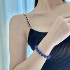 Close-up portrait shot of a woman wearing the Celestial Lapis Bracelet on a right arm extended across her chest.