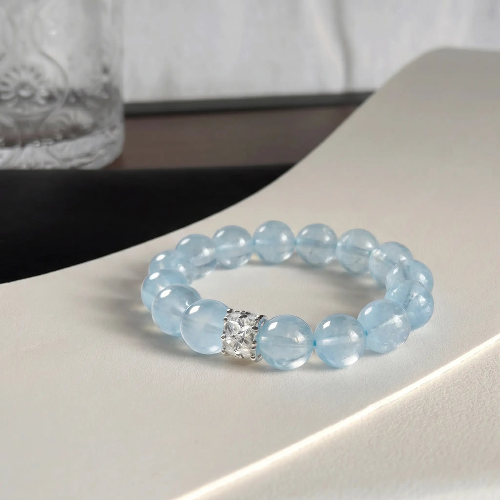 Close-up shot of the coastal elegance aquamarine bracelet adorned on a woman wrist against dark textured clothing.