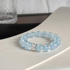 Close-up shot of the coastal elegance aquamarine bracelet adorned on a woman wrist against dark textured clothing.