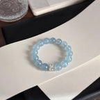 Top-down high angle shot of the coastal elegance aquamarine bracelet centered over a curved white display surface.