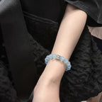 Close-up shot of the coastal elegance aquamarine bracelet adorned on a woman wrist against dark textured clothing.