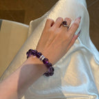 Close-up portrait view of a female wrist wearing the Eternal Elegant Amethyst Bracelet resting over shining white silk fabric.