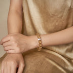 Detailed view of a seated lady with overlapping hands resting over her knee showing a red mineral gemstone bracelet.