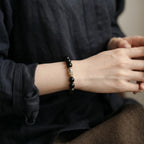 Horizontal close-up shot of a female right arm extending from left to right showcasing a golden enameled bracelet against her upper body.