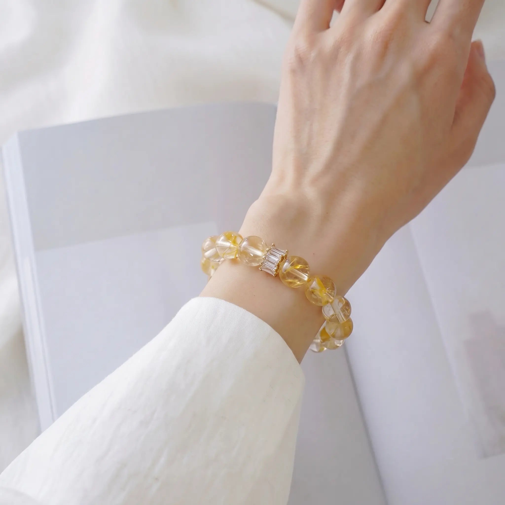 Close-up shot of a female left wrist elegantly adorned with a golden healer crystal quartz bracelet.