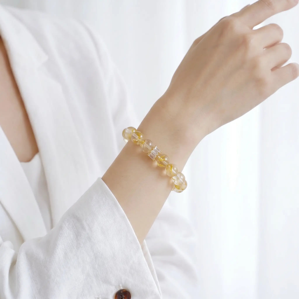 A raised right forearm perspective showcasing the fine details of a natural yellow mineral beaded bracelet.