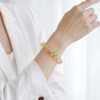 A raised right forearm perspective showcasing the fine details of a natural yellow mineral beaded bracelet.