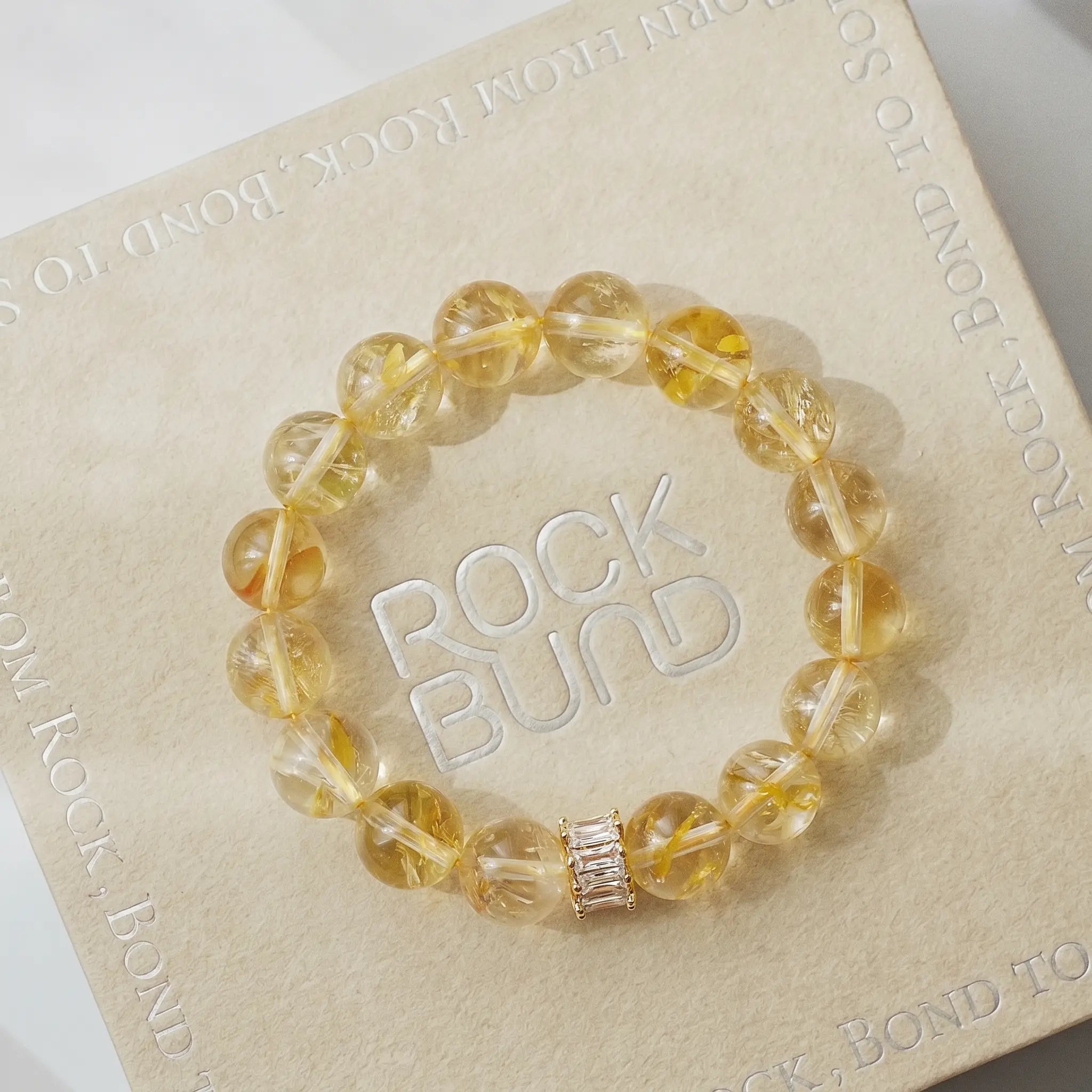 A high-quality golden healer gemstone bracelet resting flat over a soft white cloth handkerchief.