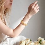 Right-side perspective close-up of a woman raised hand resting over her thigh showcasing a lemon quartz bracelet.