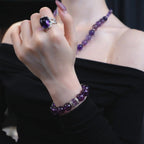 Close-up view of overlapping hands presenting the graceful amethyst poise bracelet crystal against a black off-the-shoulder top.