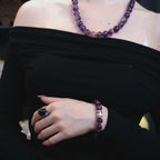 Mid-shot portrait of a woman wearing the graceful amethyst poise bracelet crystal on a bent left arm across her abdomen.