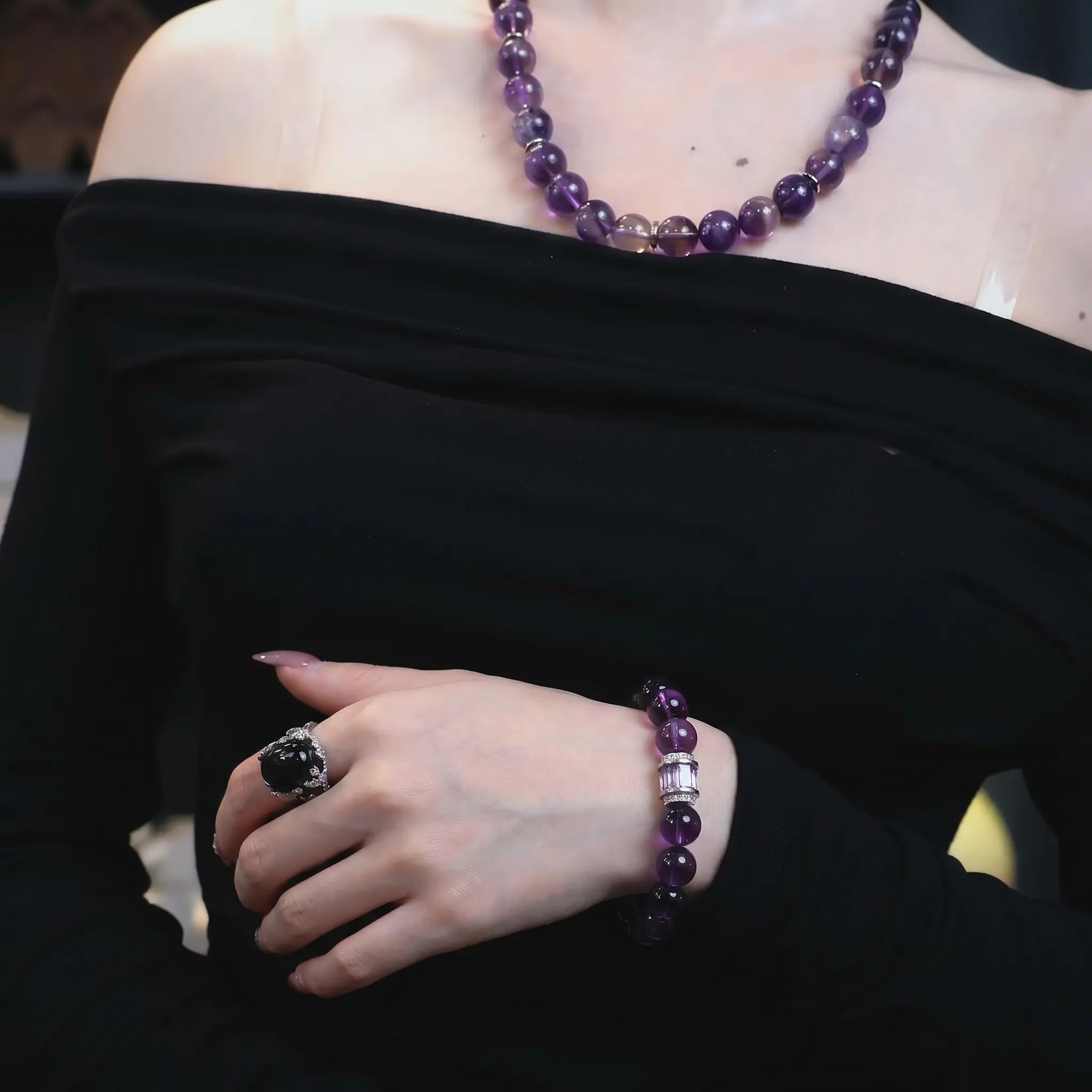 Mid-shot portrait of a woman wearing the graceful amethyst poise bracelet crystal on a bent left arm across her abdomen.