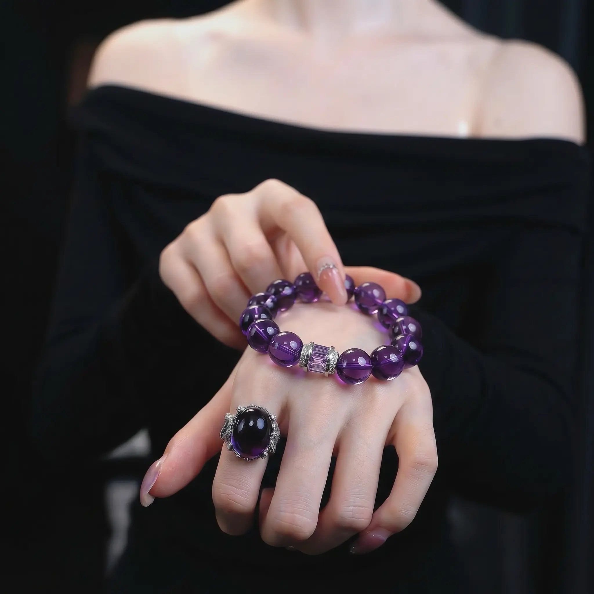 Close-up view of overlapping hands presenting the graceful amethyst poise bracelet crystal against a black off-the-shoulder top.
