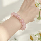 Detailed close-up shot focusing on the natural texture of a pink rose quartz beaded bracelet on a female wrist.