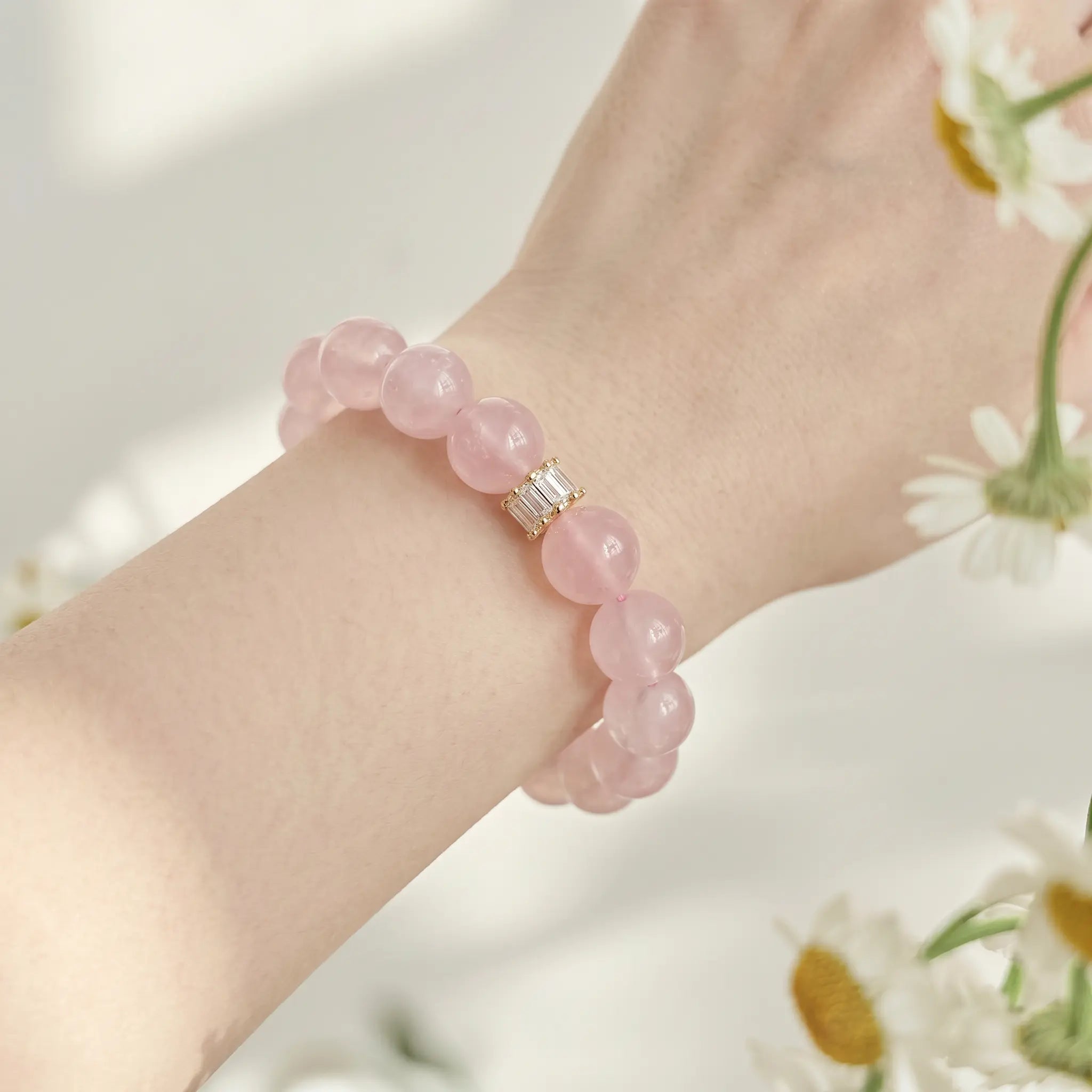 Detailed close-up shot focusing on the natural texture of a pink rose quartz beaded bracelet on a female wrist.