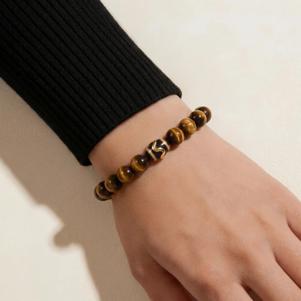 Detailed diagonal shot extending from upper-left to lower-right focusing on a mineral crystal bracelet with a patterned Dzi bead.