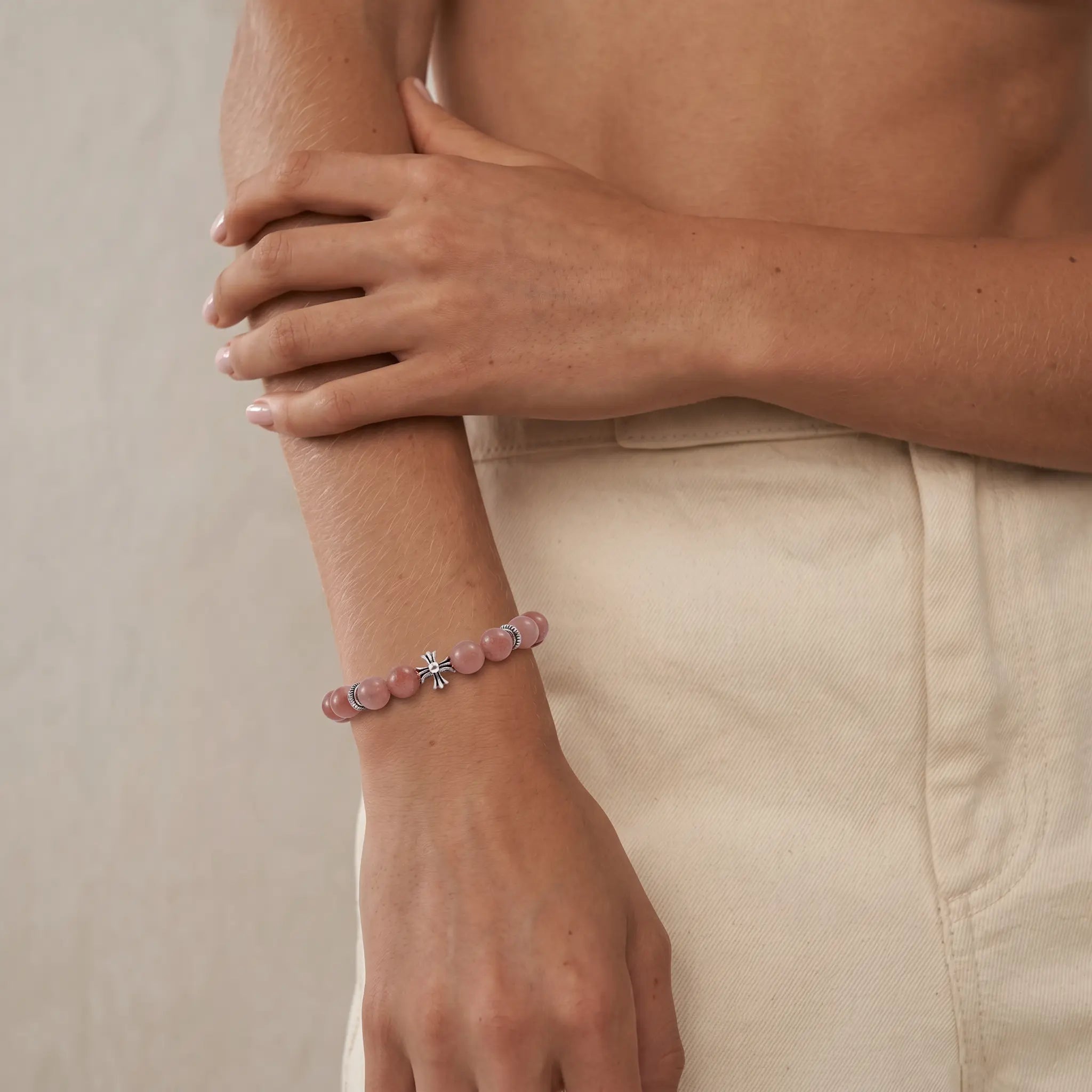 Detailed view from elbow to right hip showcasing overlapping arms while the right hand rests naturally with a gemstone bracelet.