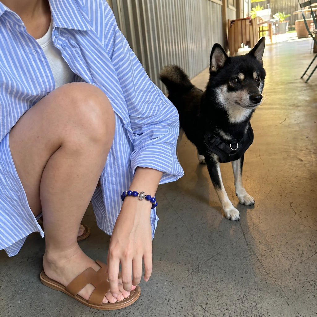 Close-up view of a woman in a crouching posture with her left elbow resting on the knee showing her lapis bead bracelet.