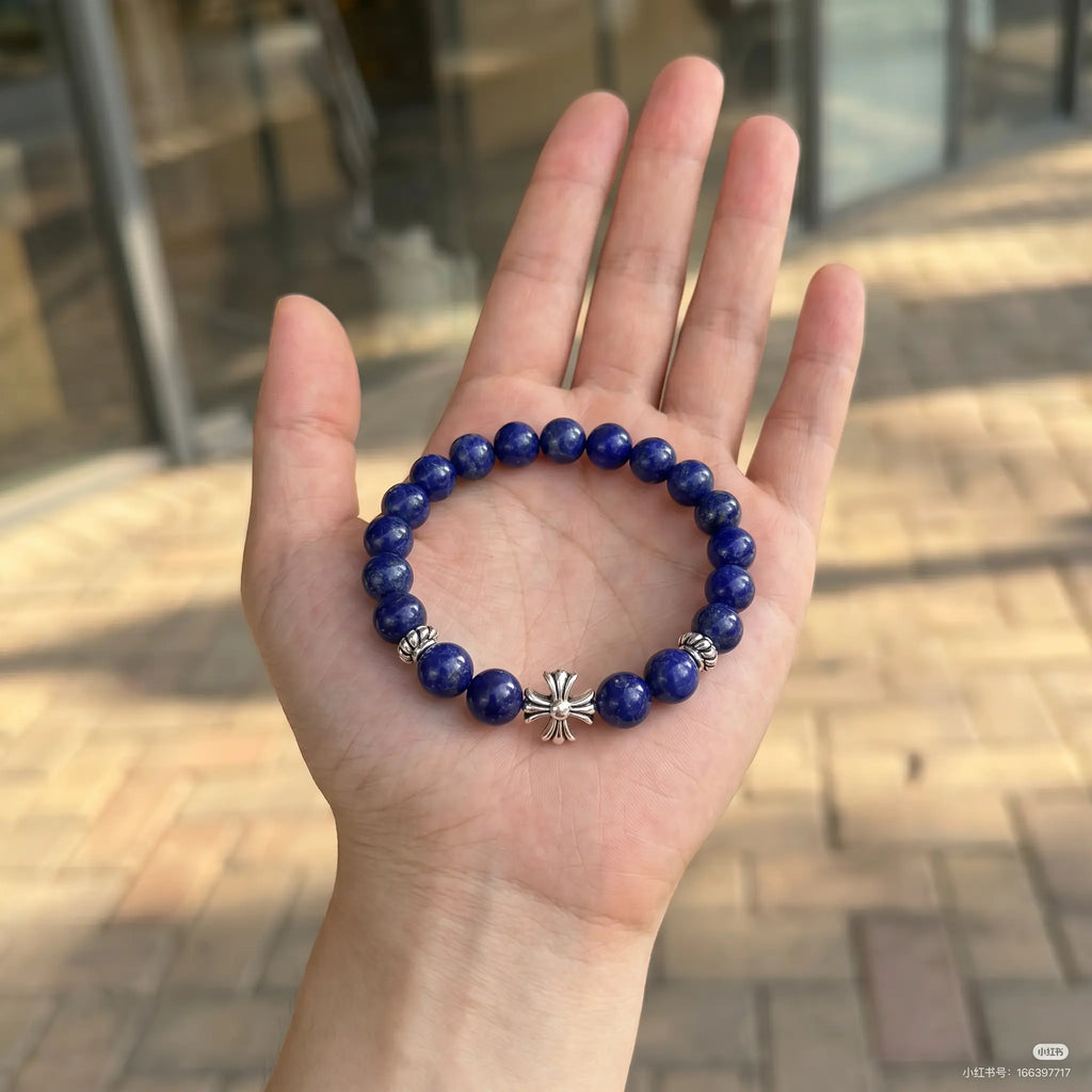Macro shot of the lapis lazuli cross bracelet resting flat inside an open palm upward showing fine jewelry details.