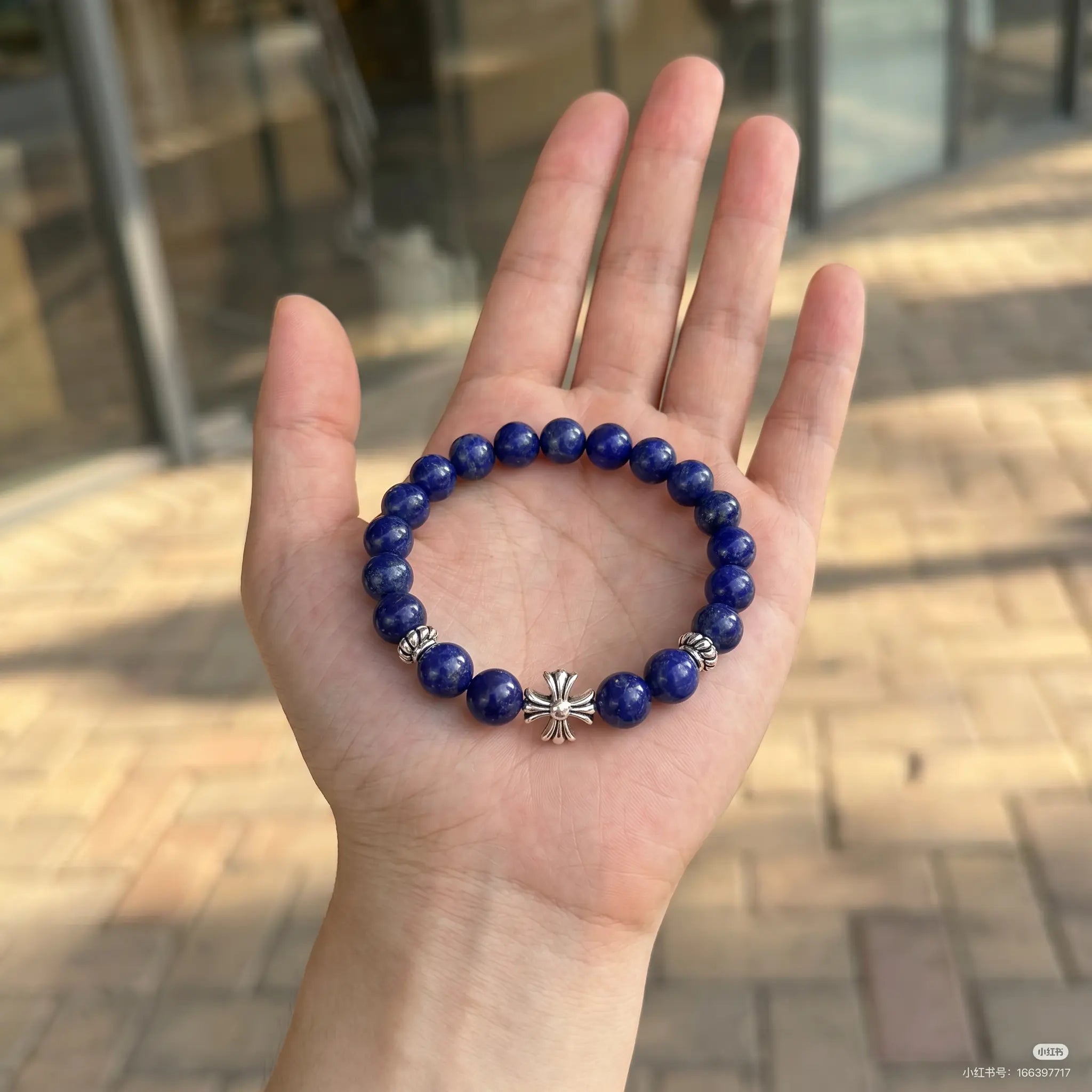 Macro shot of the lapis lazuli cross bracelet resting flat inside an open palm upward showing fine jewelry details.