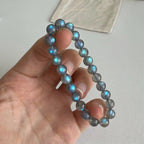 Close-up shot of fingers holding a genuine Mystic Moonstone Bracelet showing electric blue flash luminosity.