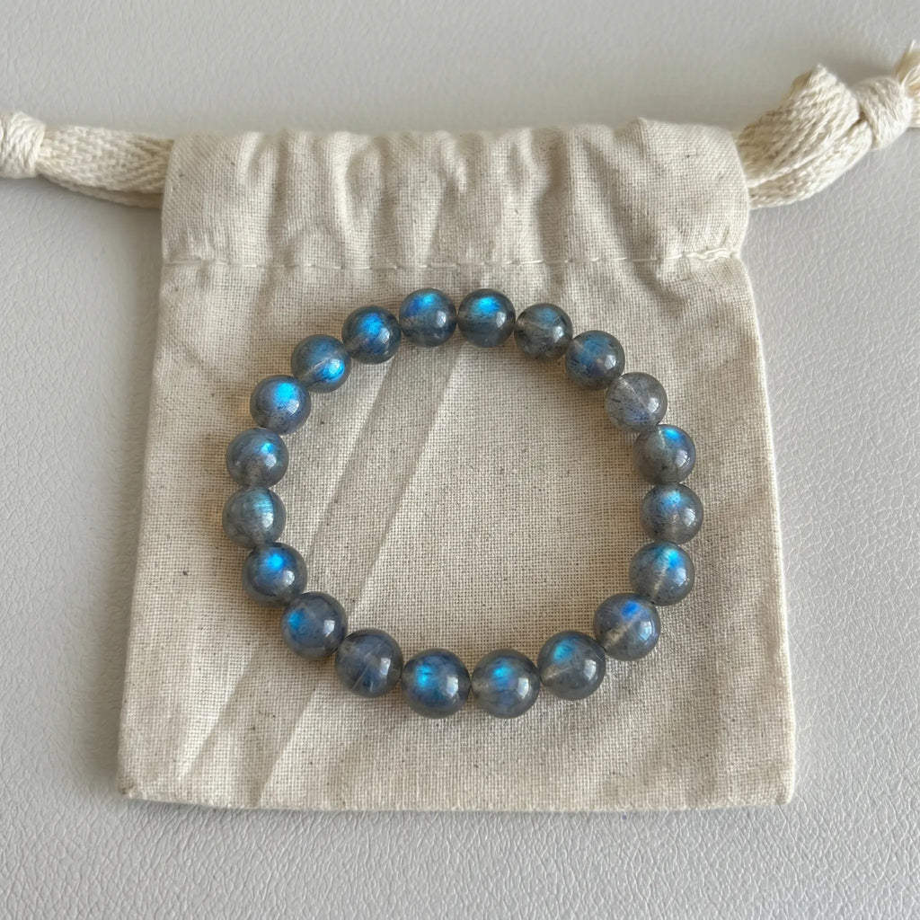 Mystic Moonstone Bracelet displayed elegantly flat on top of a natural cotton drawstring packaging pouch.