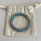 Mystic Moonstone Bracelet displayed elegantly flat on top of a natural cotton drawstring packaging pouch.