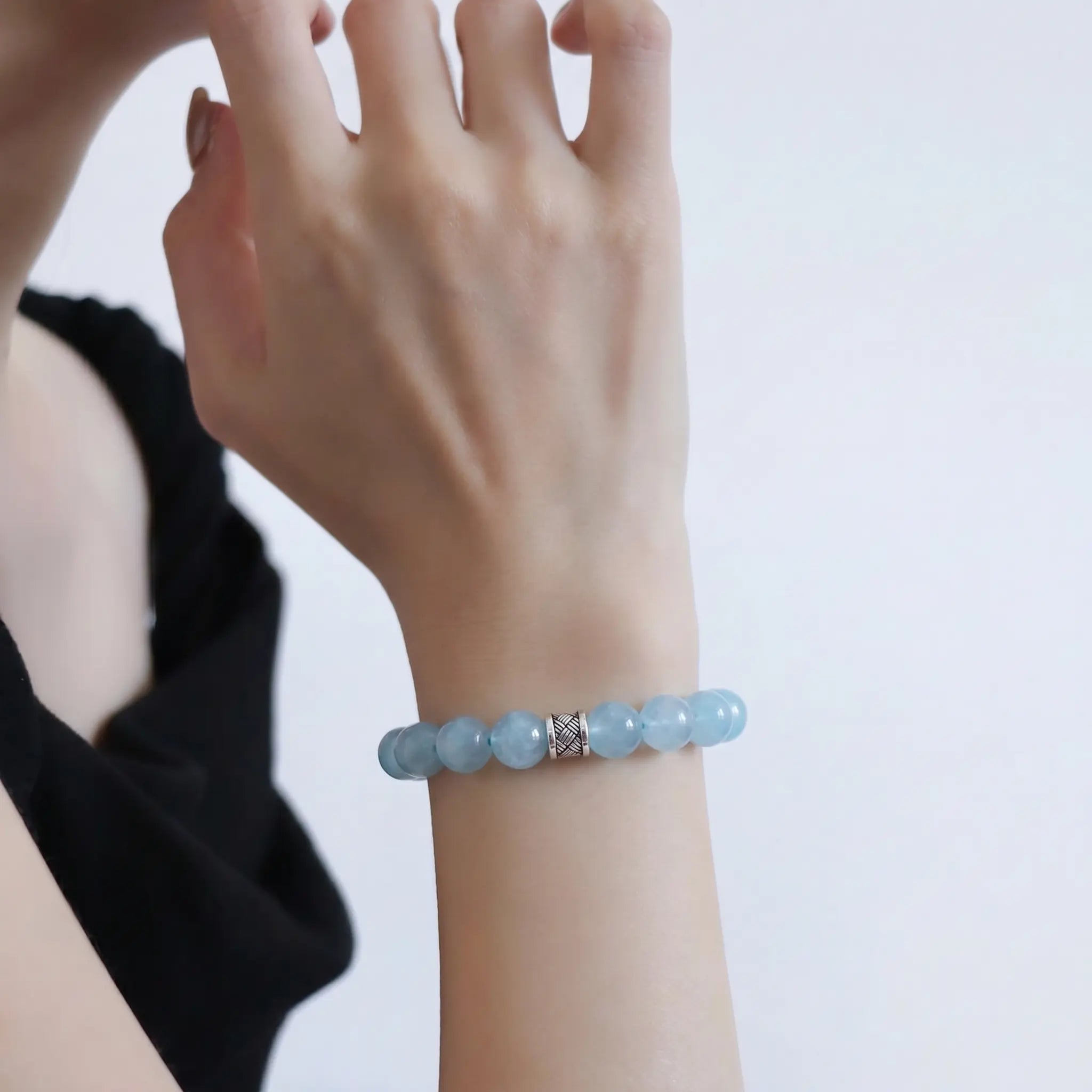 Front view portrait up to the chin showing a lady right forearm raised vertically wearing the ocean’s grace aquamarine bracelet 