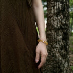 Detailed close-up shot of a female left hand resting naturally downward showcasing the golden aura gemstone bracelet.