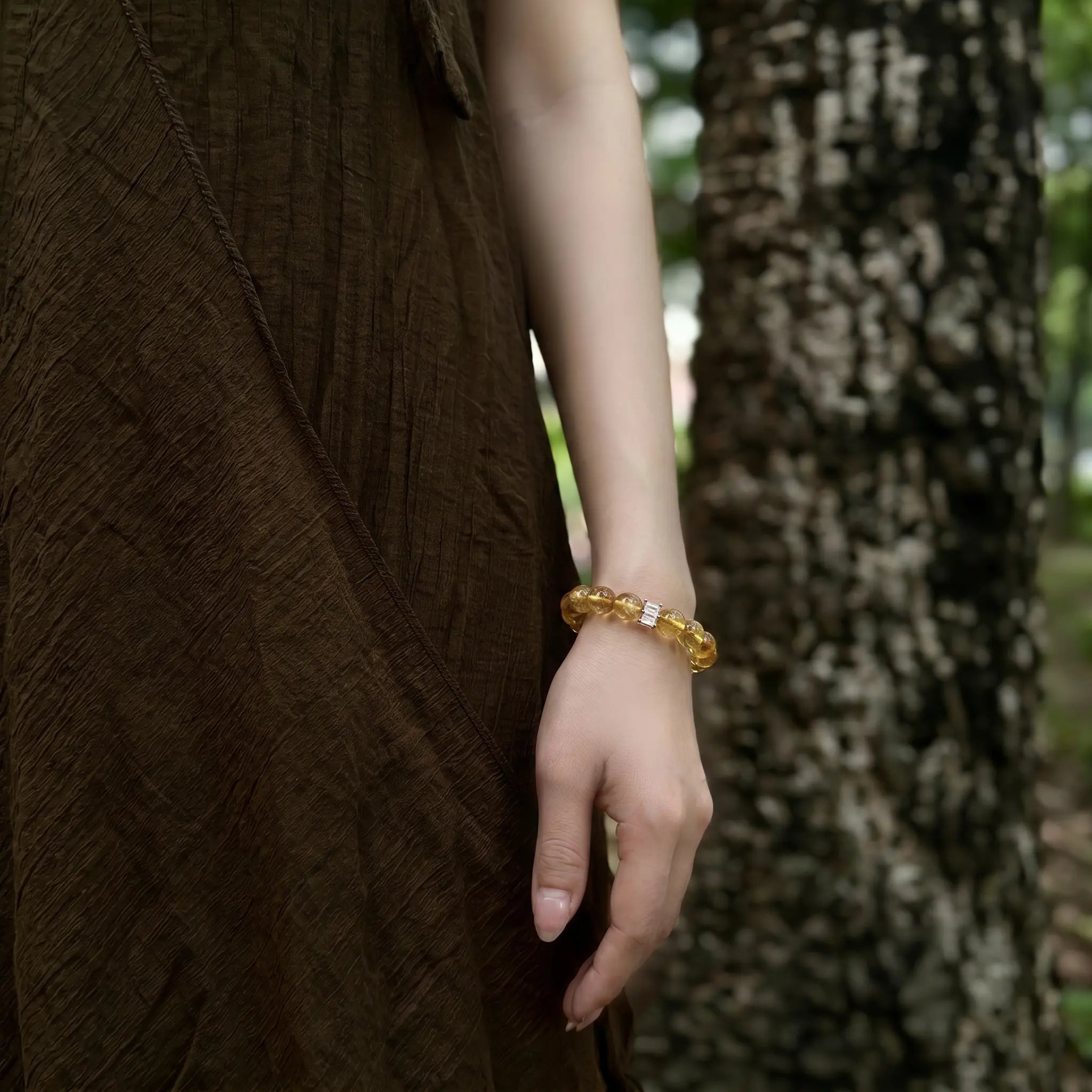 Detailed close-up shot of a female left hand resting naturally downward showcasing the golden aura gemstone bracelet.