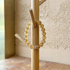 A luxury quartz crystal bracelet displayed elegantly by hanging on a rustic wooden stand artifact.