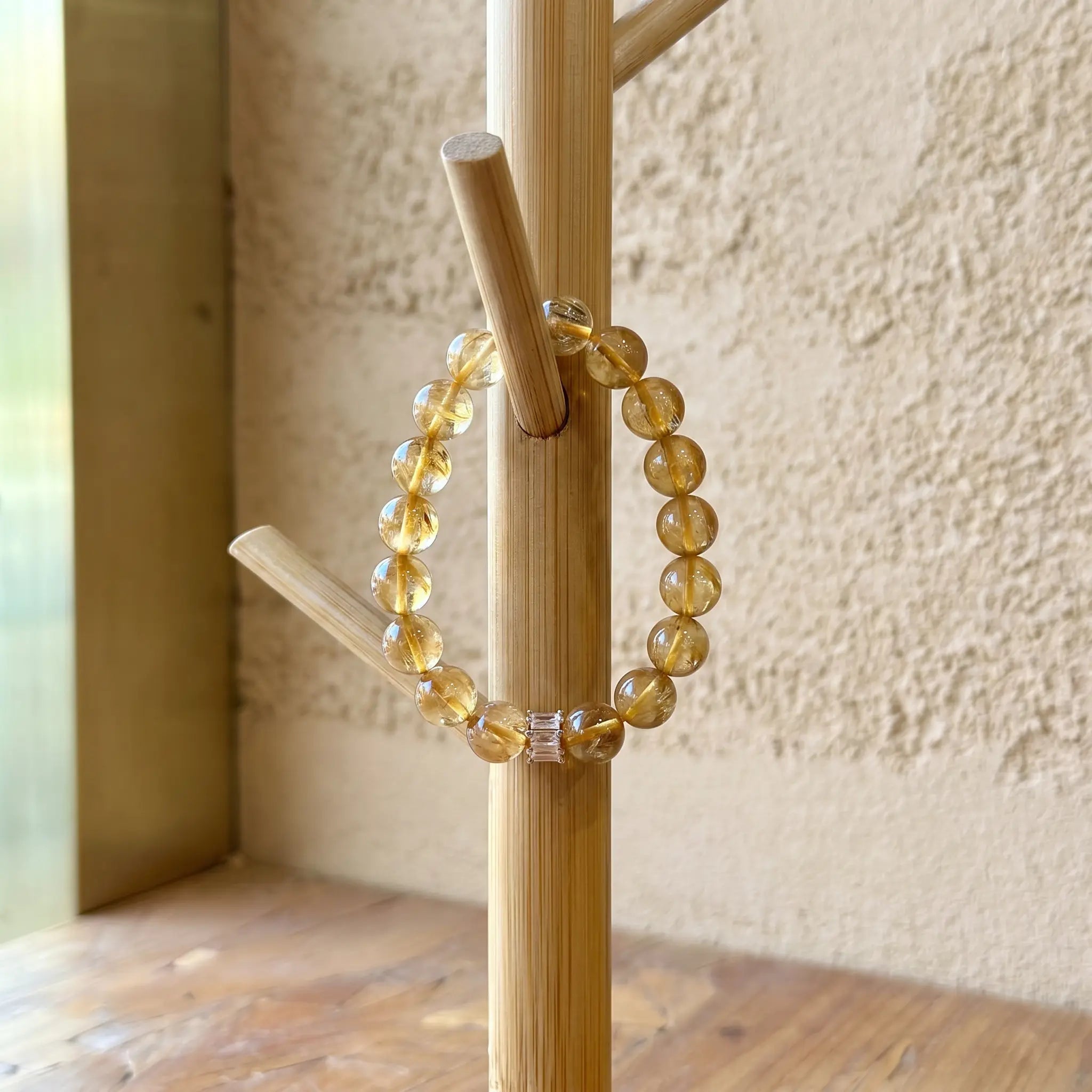 A luxury quartz crystal bracelet displayed elegantly by hanging on a rustic wooden stand artifact.