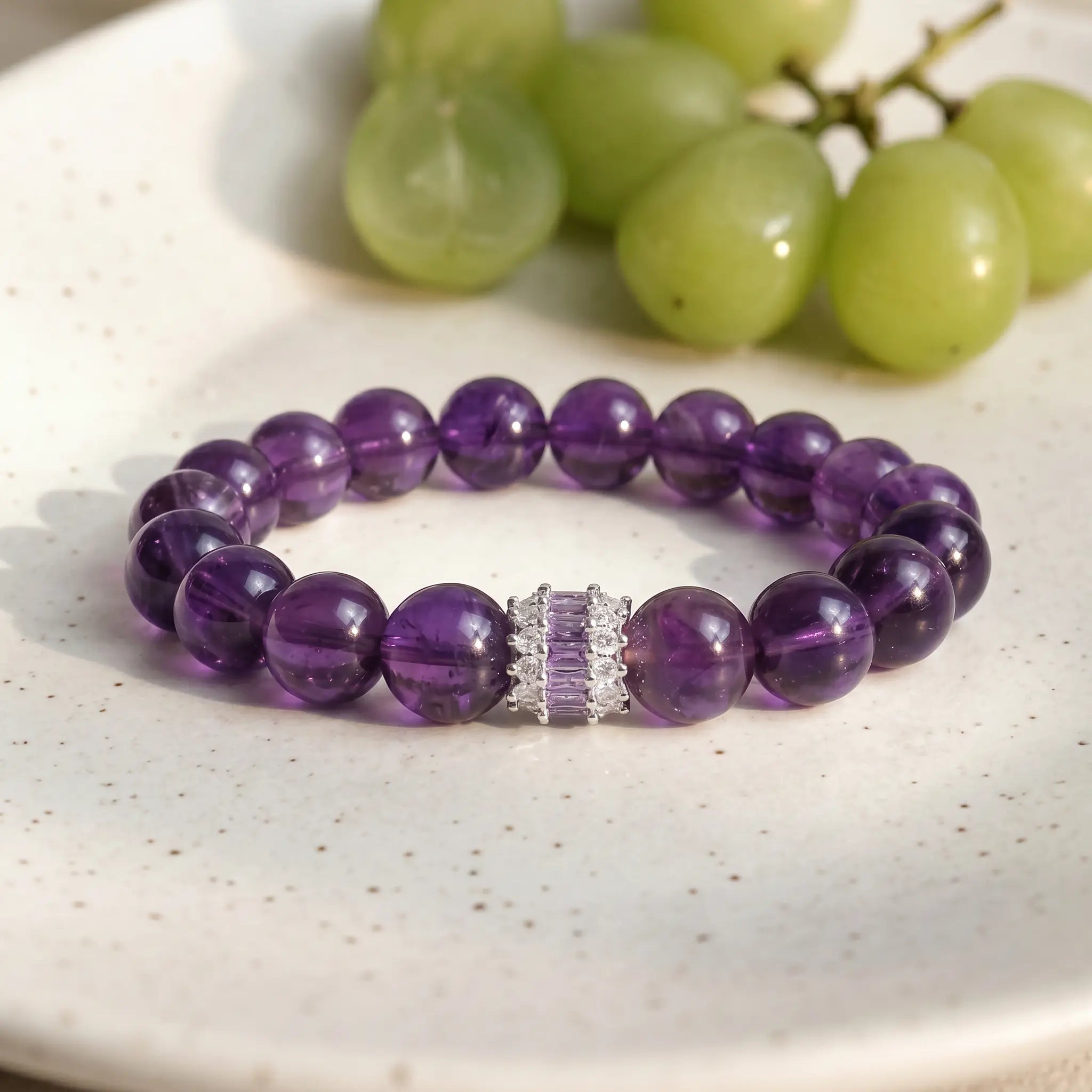 A high-end royal purple amethyst crystal bracelet displayed flat on a luxury ceramic porcelain plate.