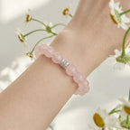 Enlarged extreme close-up view focusing on the fine texture of a pink mineral quartz beaded bracelet on a wrist.