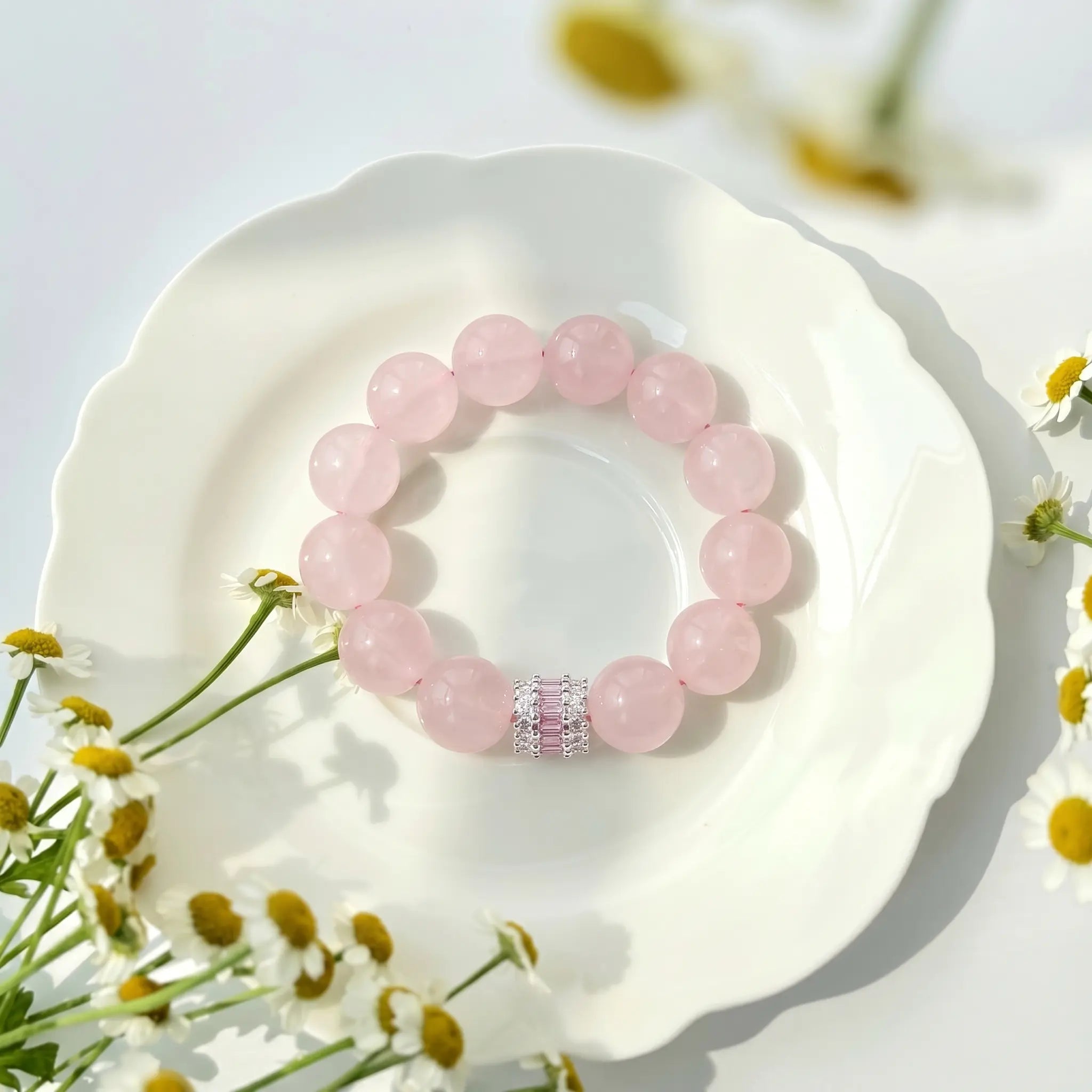 A premium pink quartz energy gemstone bracelet displayed flat on a luxury ceramic porcelain plate.