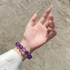 Detailed shot extending from lower-left to center focusing on an open palm upward revealing a purple quartz bracelet on the wrist.