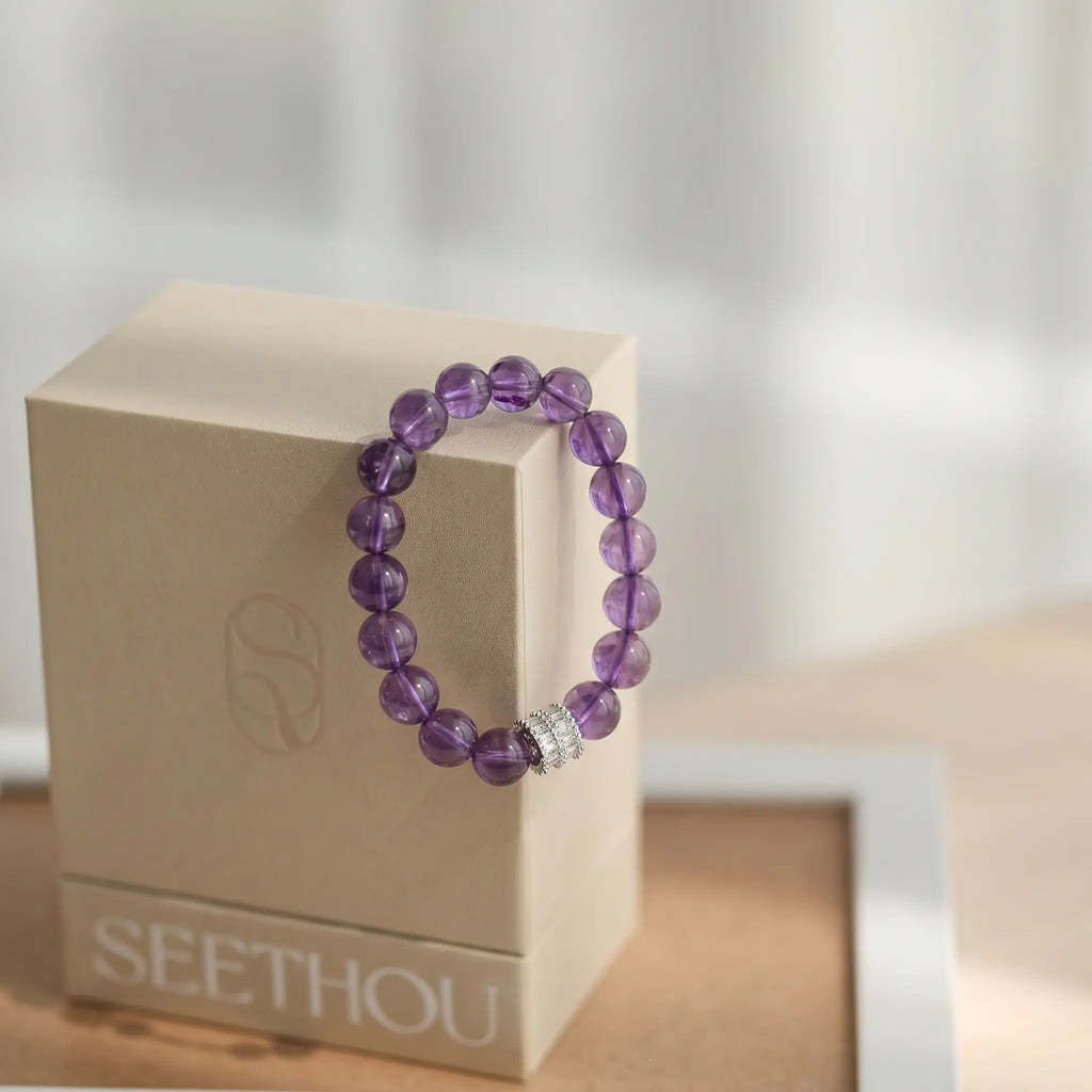 A fine gemstone crystal bracelet displayed elegantly by hanging precisely on the corner of a square box.