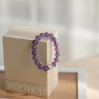 A fine gemstone crystal bracelet displayed elegantly by hanging precisely on the corner of a square box.