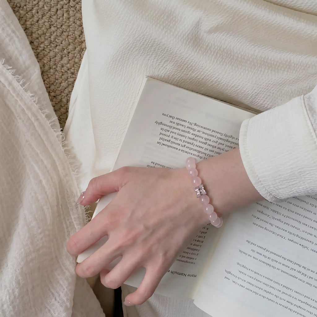 Artistic portrait view of a lady wrist styled with a quartz energy bracelet clutching a hardcover book.