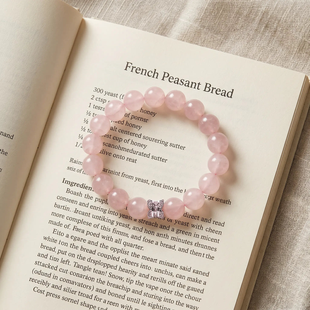 Close-up shot of the Serenity Heart Rose Quartz Bracelet placed gracefully on the pages of an open book.