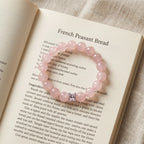 Close-up shot of the Serenity Heart Rose Quartz Bracelet placed gracefully on the pages of an open book.