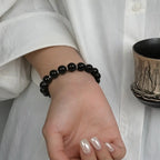 Detailed close-up view of a female wrist showing the lower palm side styled with a black gemstone bracelet.