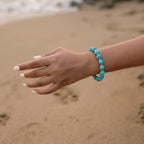 Detailed close-up view of a woman left wrist elegantly styled with a blue gemstone beaded bracelet.