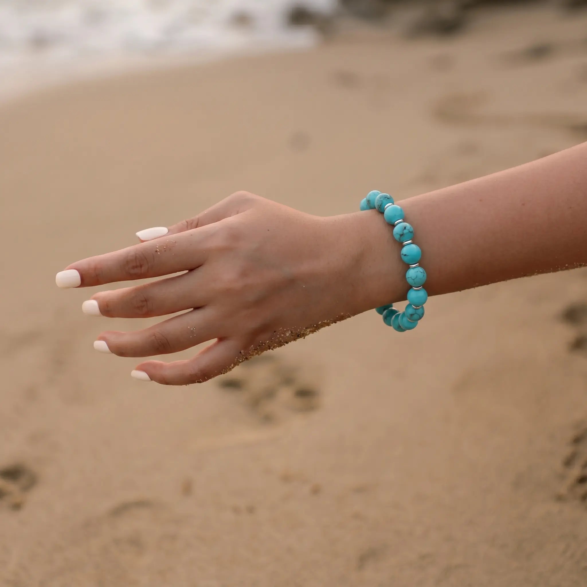 Detailed close-up view of a woman left wrist elegantly styled with a blue gemstone beaded bracelet.