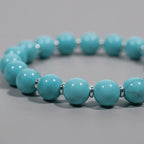 Cropped right-side half-view of the lucky blue turquoise crystal bracelet on a neutral grey background.